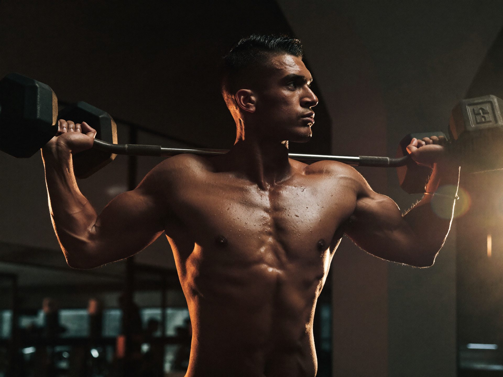 An athlete performing a dumbbell press in a gym